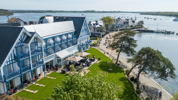 A waterfront hotel with a terrace and outdoor seating area. - Best Western Plus Hôtel Le Roof (Vannes)