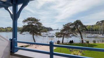 Vista desde un balcón sobre un puerto deportivo con barcos y árboles.