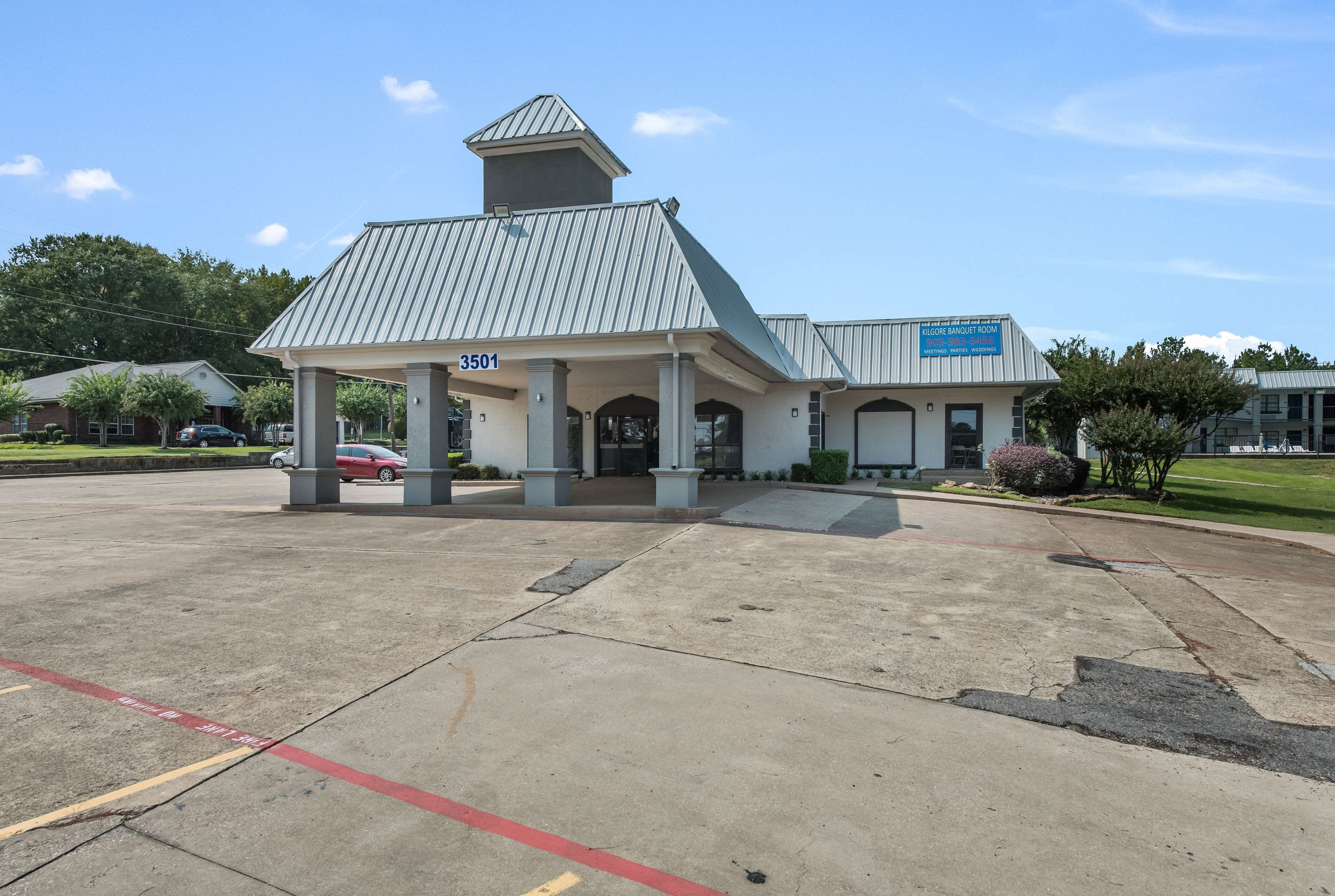 A building with a covered entrance, a sign indicating a banquet room, and a parking lot with marked spaces.