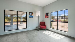 A spacious room with large windows, a red chair, and a floor lamp. - Motel 6 Kilgore, TX (Kilgore)