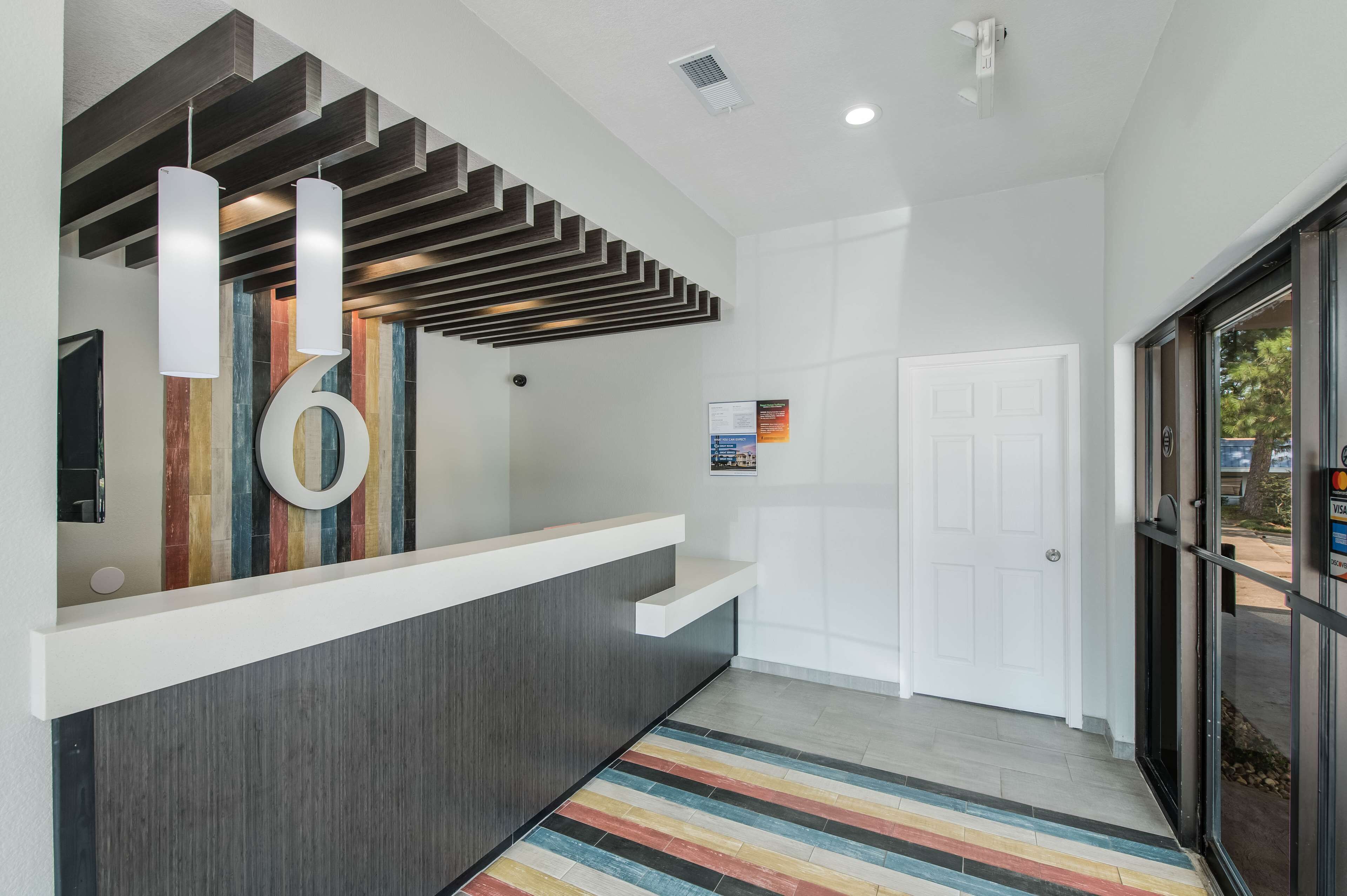 Un espace d’accueil au design moderne, comprenant un comptoir d’accueil en bois, un tapis rayé aux couleurs vives et une grande œuvre d’art circulaire accrochée au mur.