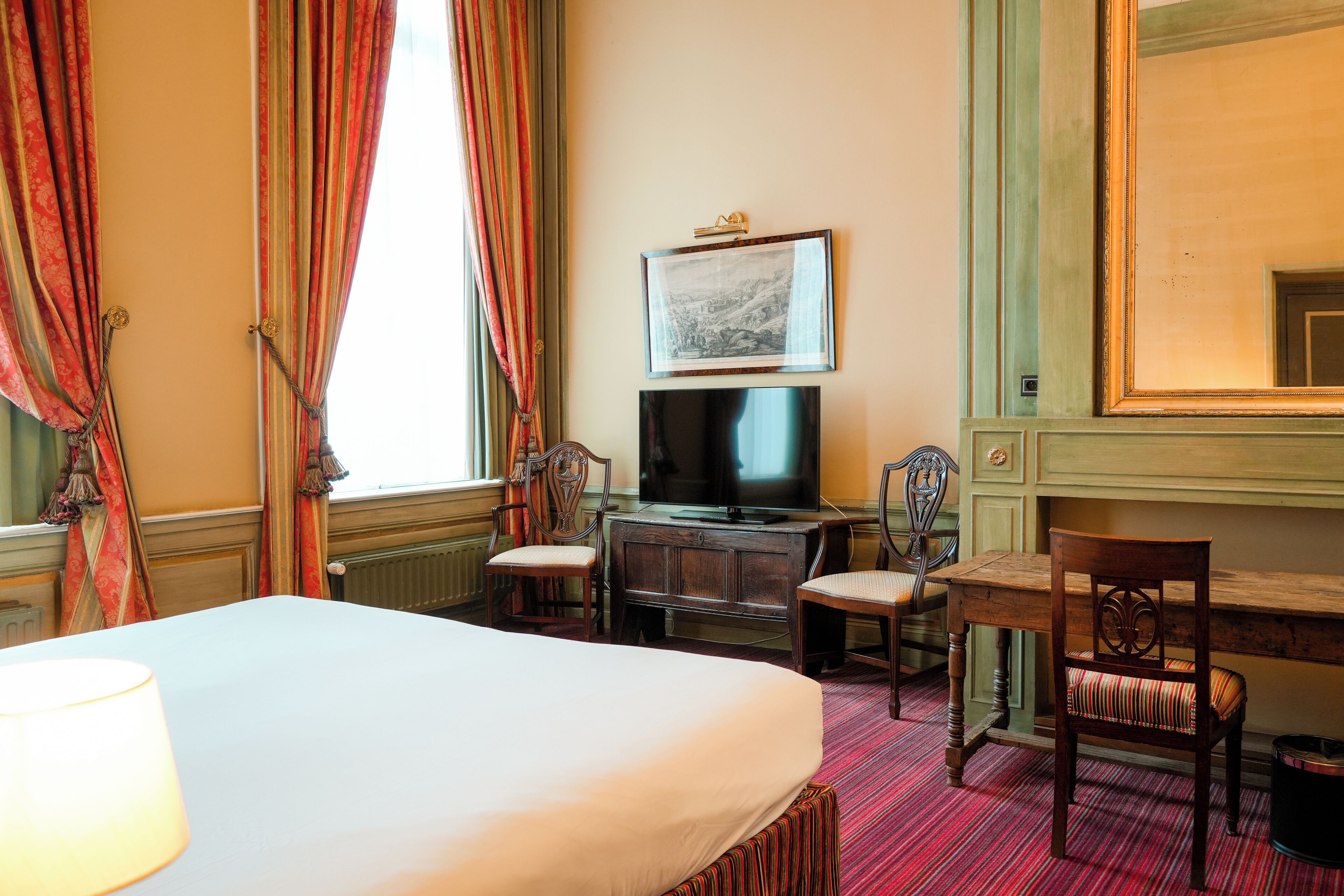 Una habitación de hotel con cama, escritorio, televisor y una silla.