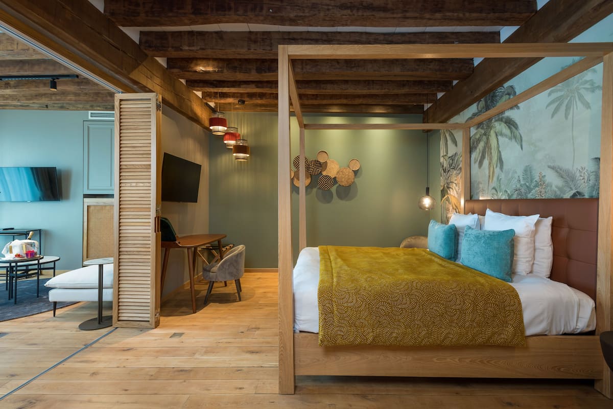 Un dormitorio con una cama de madera con dosel, un televisor, un escritorio y una silla.