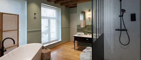 A modern bathroom with a freestanding bathtub, a shower, and a vanity with a mirror.