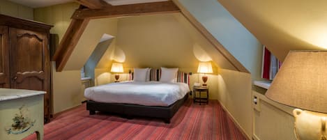 Un dormitorio con una cama grande, dos lámparas de noche, un aparador de madera y un suelo cubierto de alfombra roja.