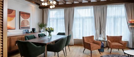 A modern dining area with a wooden table, green chairs, and a grey rug.
