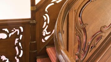 A wooden staircase with intricate carvings and a striped carpet.