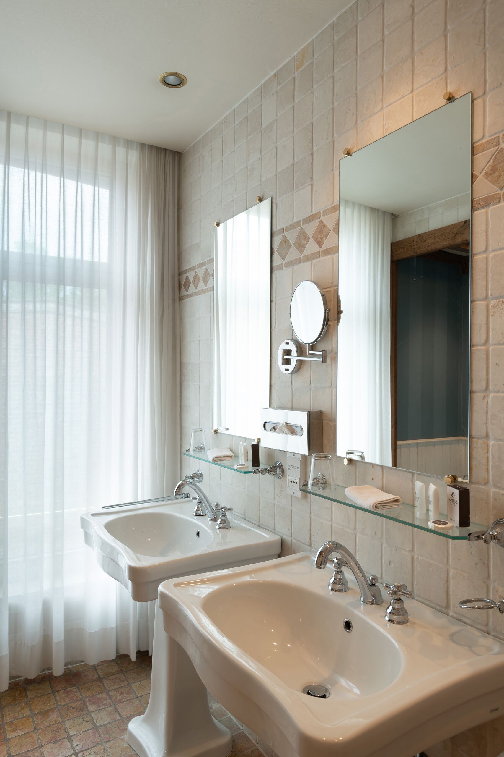 A modern bathroom with two sinks, a large mirror, and a glass shelf.
