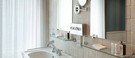 A modern bathroom with two sinks, a large mirror, and a glass shelf.