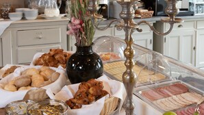 Una mesa de buffet con diversos alimentos, un jarrón con flores y velas encendidas.
