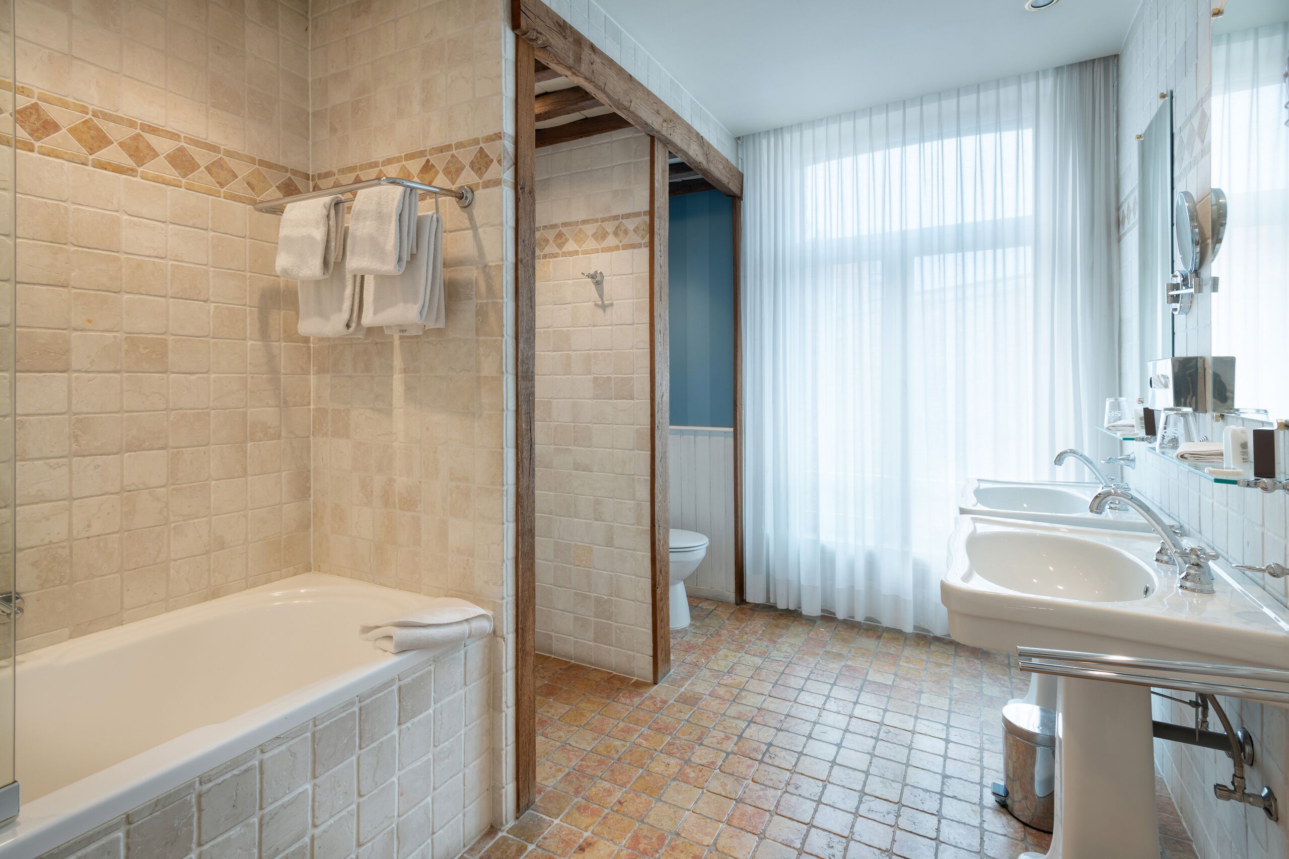 A bathroom with a bathtub, two sinks, a toilet, and a shower area.