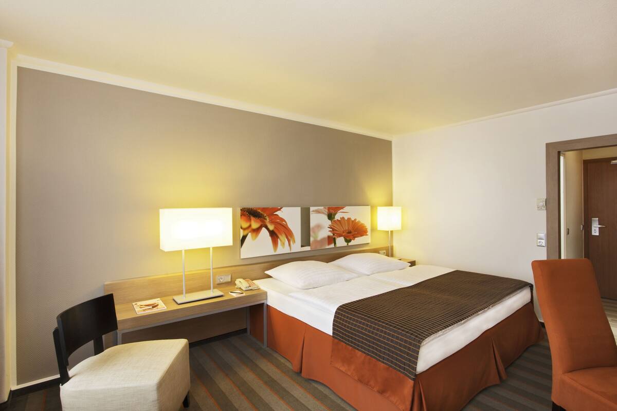 Ein Hotelzimmer mit Bett, Schreibtisch, Sessel und Nachttisch.