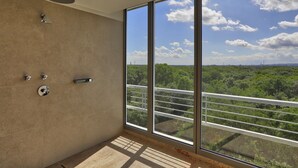Ein Badezimmer mit großem Fenster, Dusche und Blick auf Grünflächen.