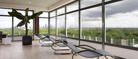 Una habitación moderna con ventanas amplias, una planta en maceta y una fila de sillones.