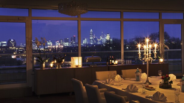 Ein Esszimmer mit Blick auf die Stadt, großen Fenstern und einem für eine Mahlzeit gedecktem Tisch.