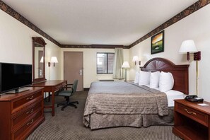 A hotel room with a bed, desk, chair, television, and lamps. - Heritage Inn (Augusta)