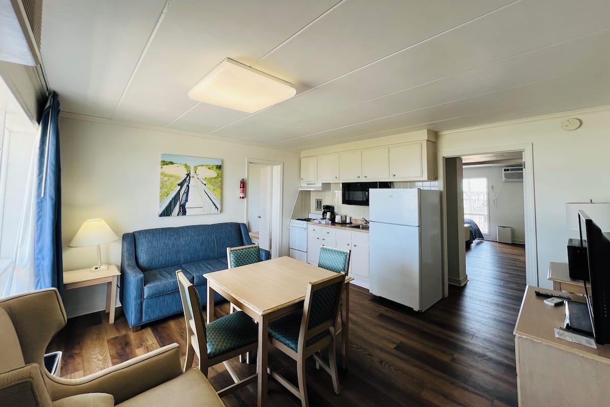 A compact room with a kitchenette, a dining area, and a sofa.