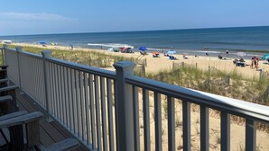 A beach view from a balcony with a wooden railing, sandy beach, and ocean. - Mariner Inn and Suites (Kill Devil Hills)