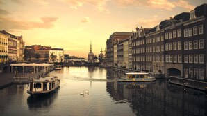 A canal with boats, historic buildings, and a tower in the background. - Hotel Europe Huis Ten Bosch (Sasebo)