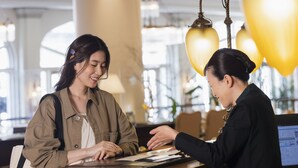 A reception desk in a hotel lobby with a modern design, featuring a wooden counter and a digital screen displaying information. - Hotel Europe Huis Ten Bosch (Sasebo)