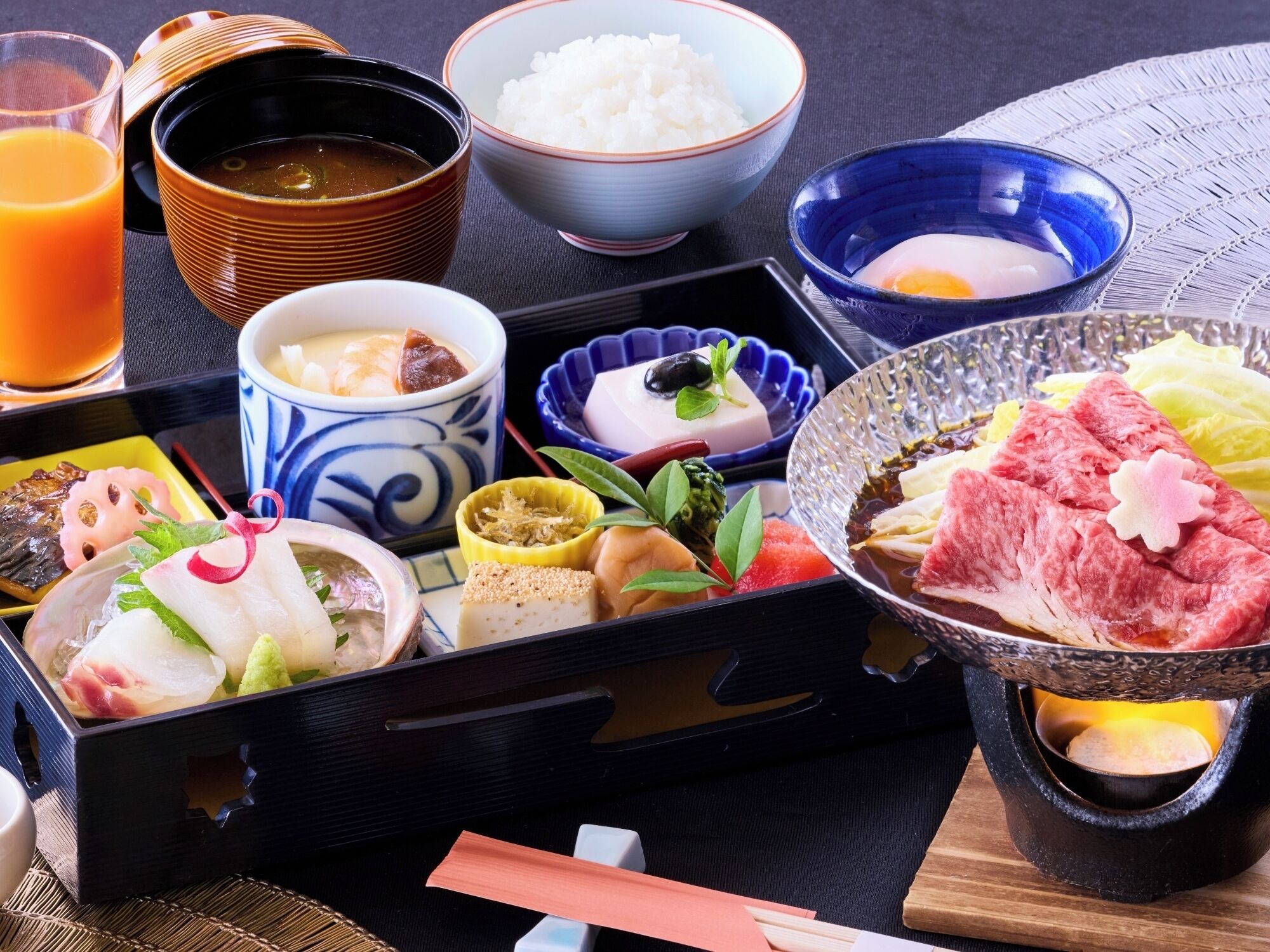 Una comida tradicional japonesa con varios platos y una bebida.