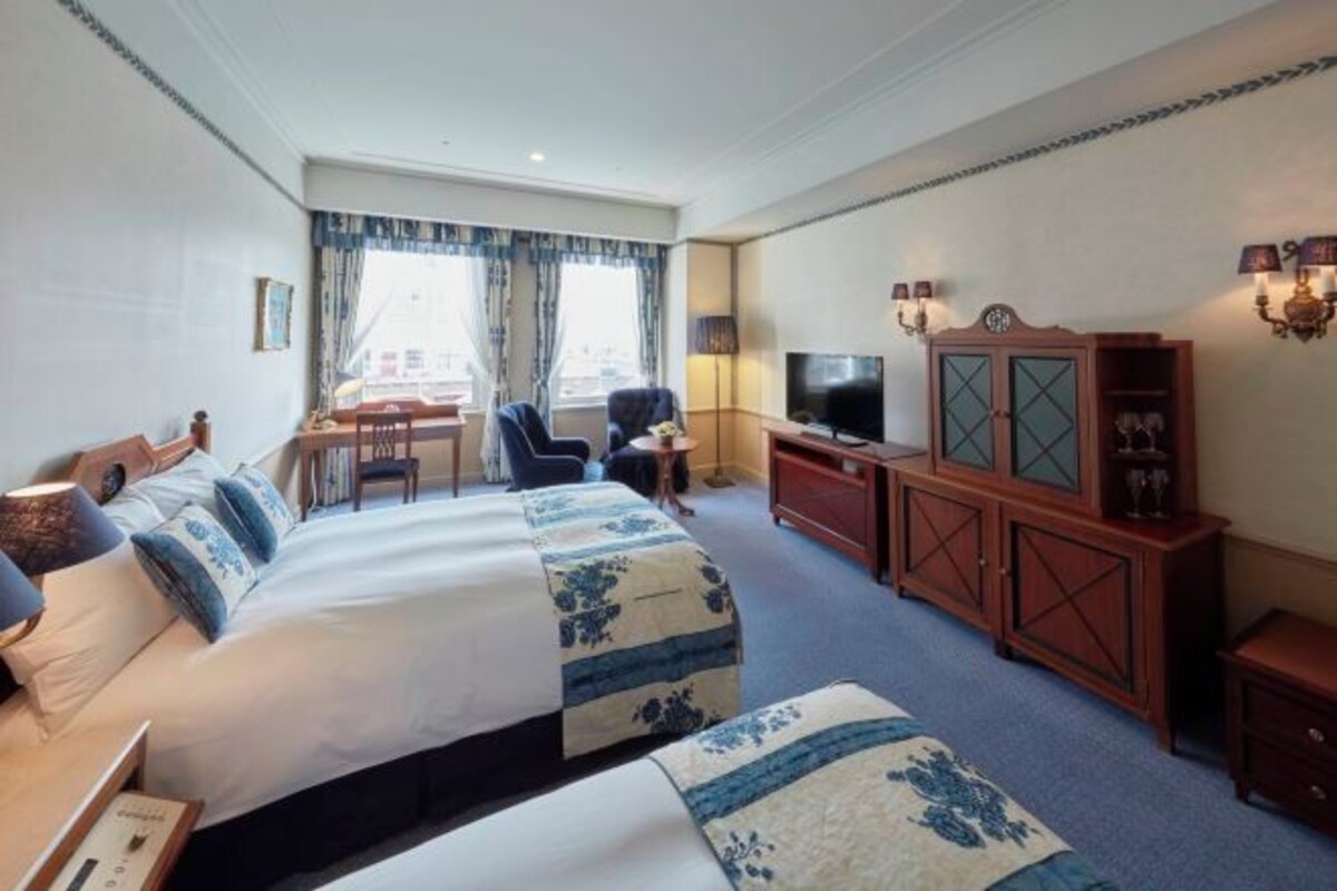 Ett hotellrum med två sängar, en TV, ett skrivbord med en stol och ett skåp.