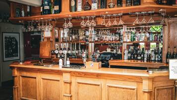 A bar with wooden shelves stocked with various liquor bottles and glasses hanging above.