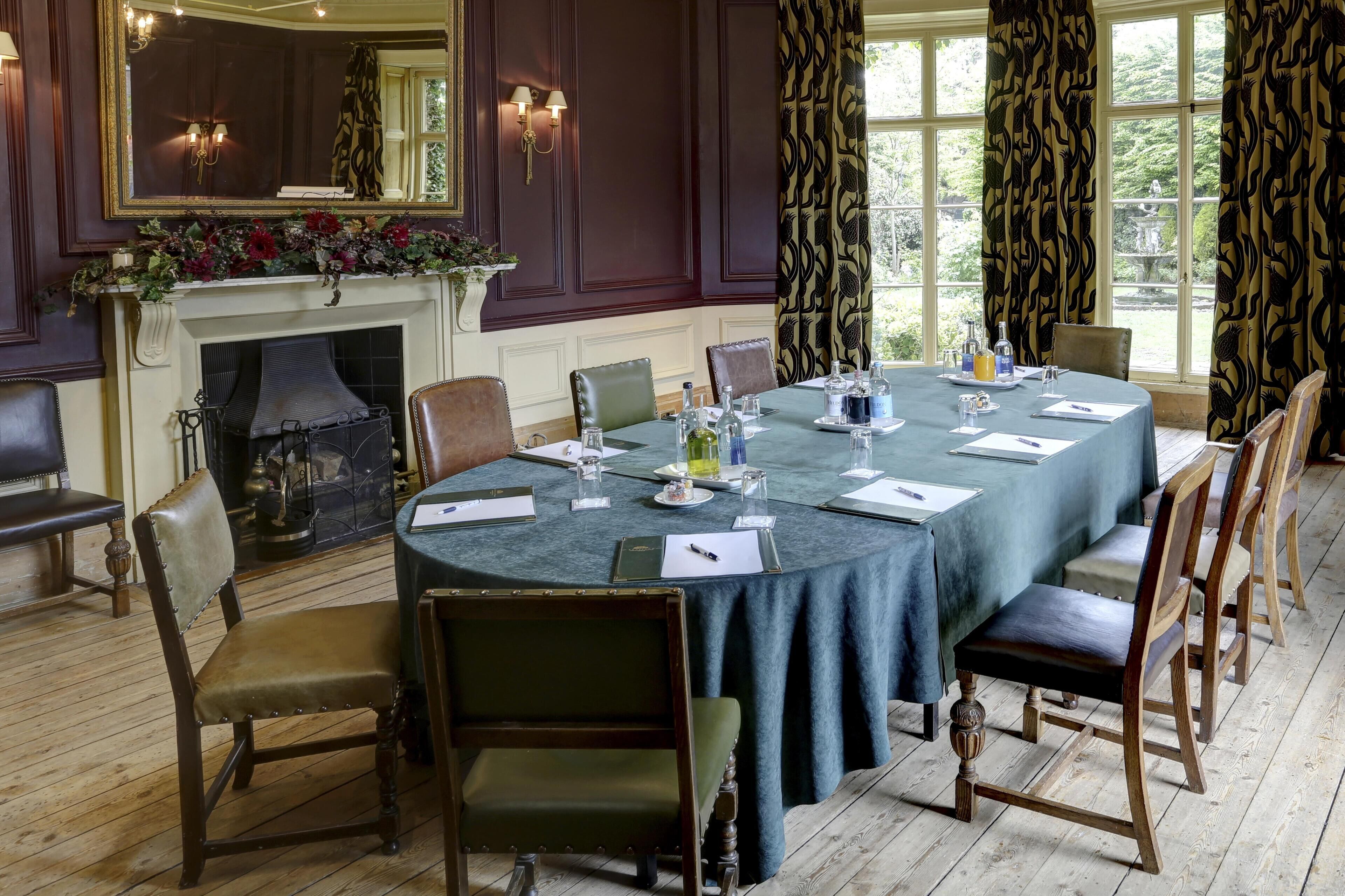 Un comedor formal con una mesa redonda, sillas, una chimenea y ventanas amplias con cortinas.