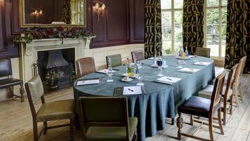 Un comedor formal con una mesa redonda, sillas, una chimenea y ventanas amplias con cortinas.