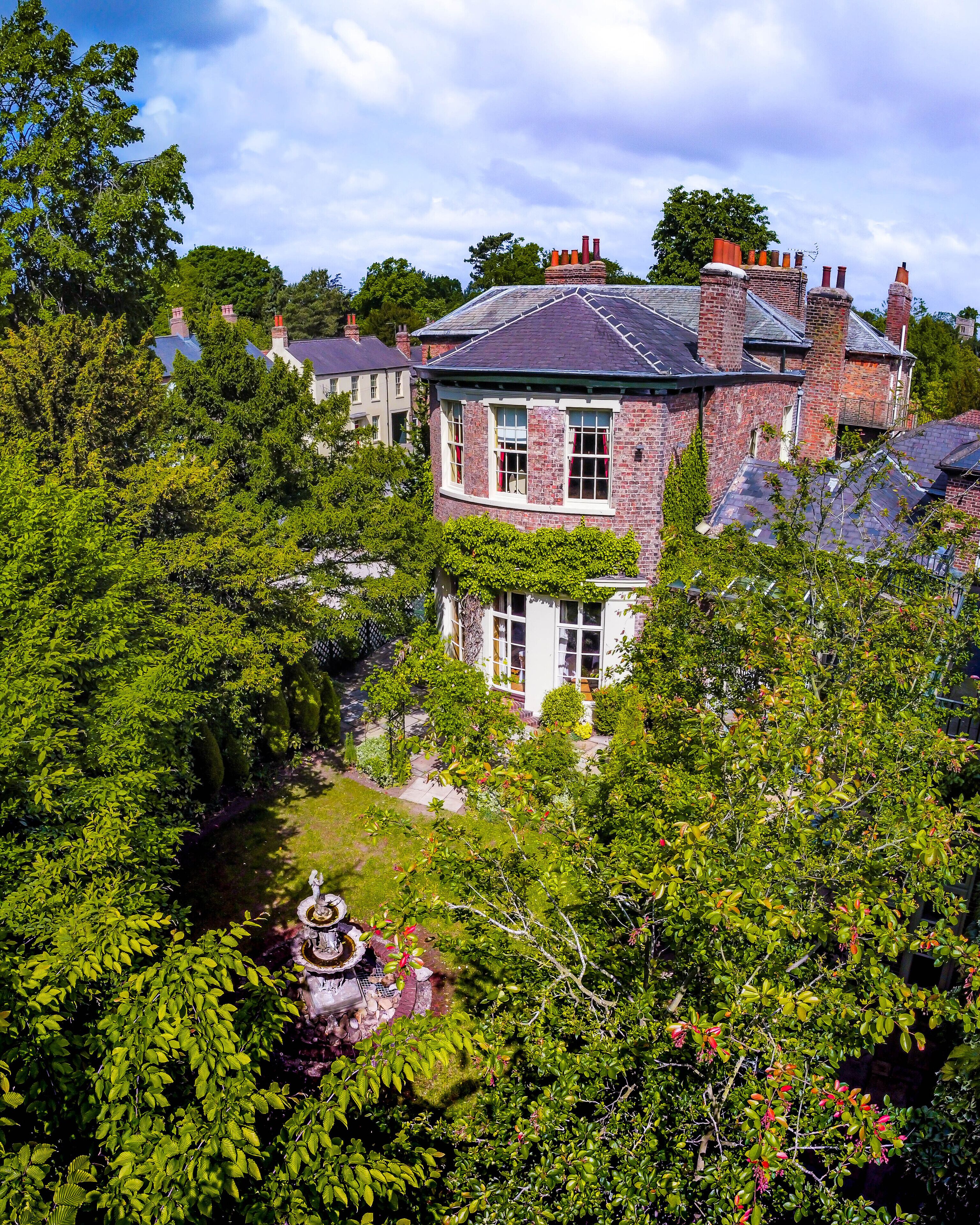 Une grande maison en briques avec un jardin et une fontaine.