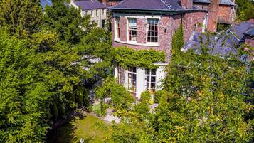 Une grande maison en briques avec un jardin et une fontaine.