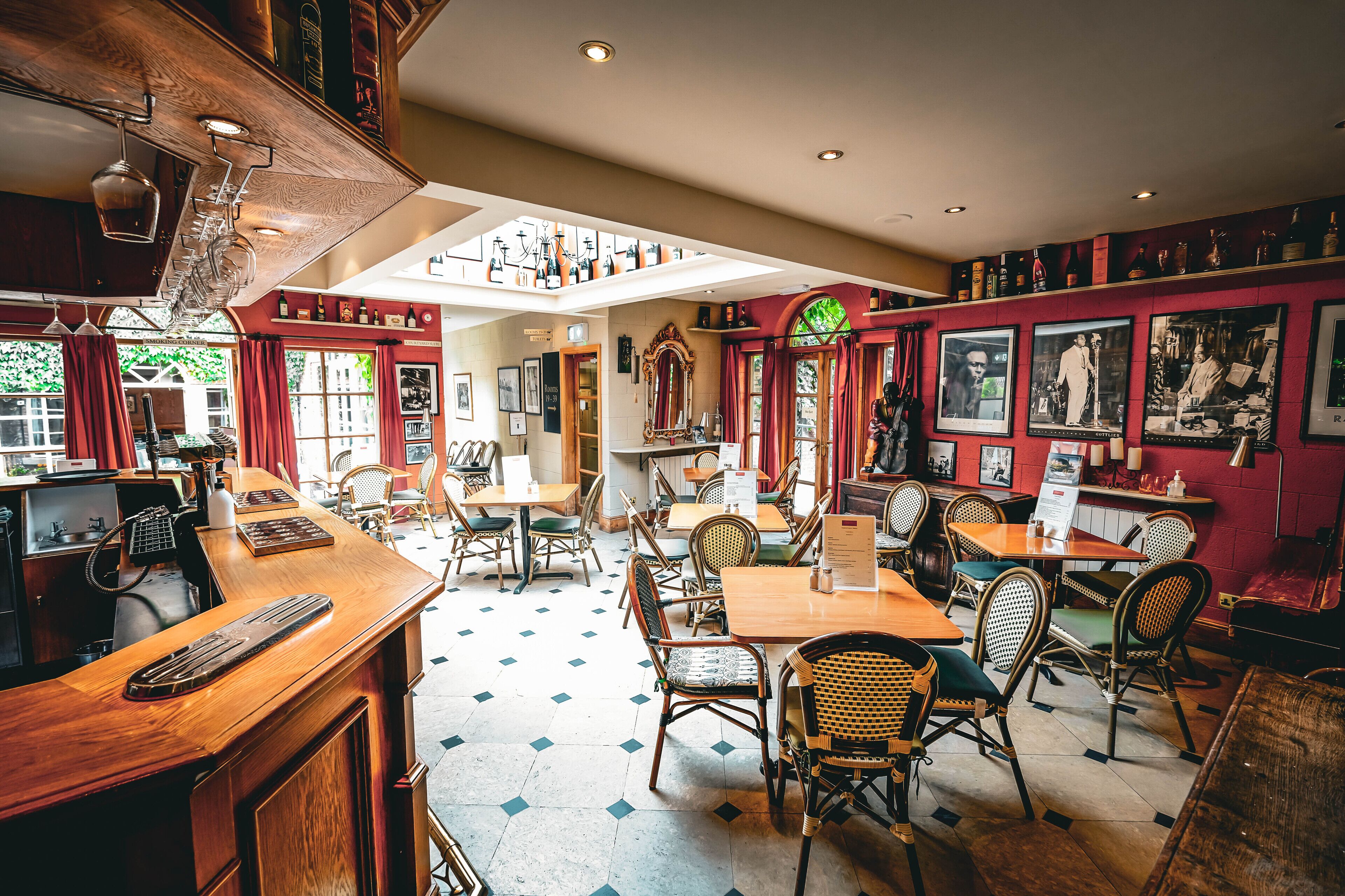 A restaurant with a high ceiling, wooden bar, and multiple dining tables and chairs.