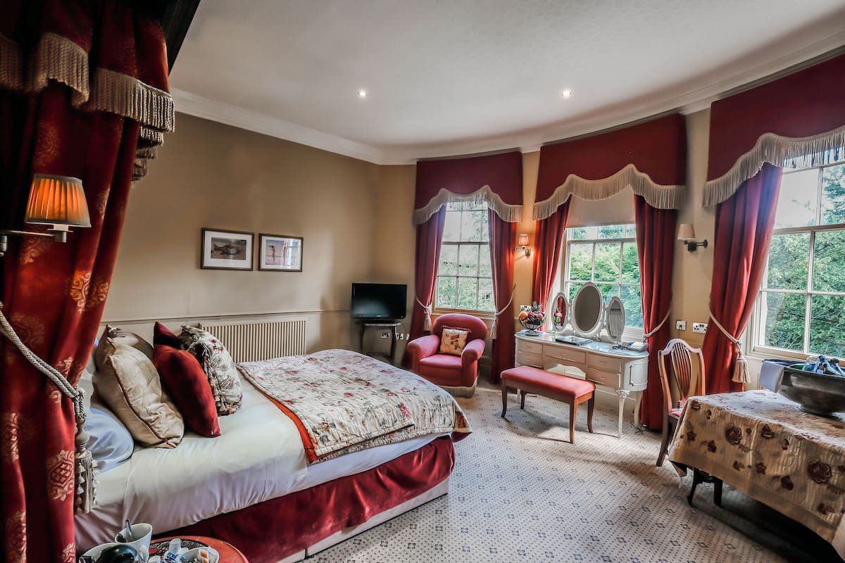 Une chambre à coucher avec un grand lit, un bureau, une chaise et une table avec une lampe.