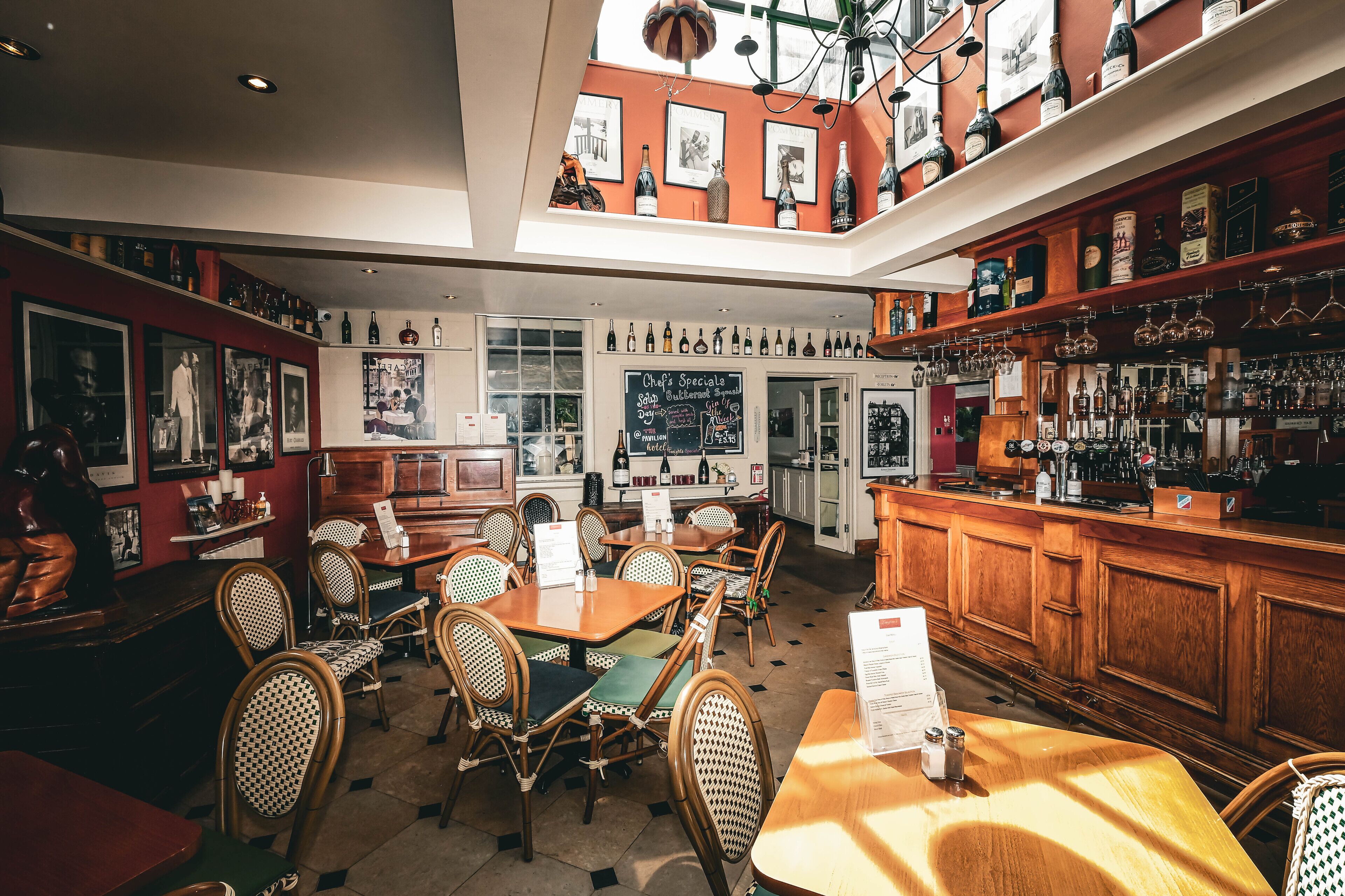 Un restaurante con mobiliario de madera, una zona de bar y un menú en pizarra.