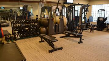A gym with various exercise equipment, including treadmills, weight machines, and free weights.