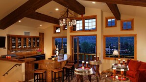 A bar area with wooden furniture, a wine rack, and large windows offering a view of the outdoors.