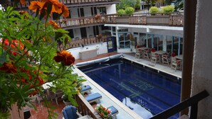 A rooftop pool area with lounge chairs and a dining area.