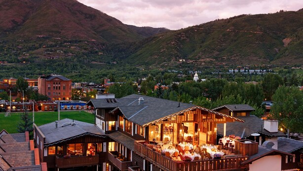 A hotel with a dining area on the second floor, surrounded by mountains.