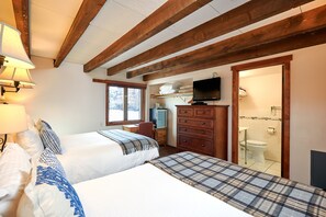 A hotel room with two beds, a desk, a television, and a bathroom visible through an open door. - Mountain Chalet Aspen (Aspen)