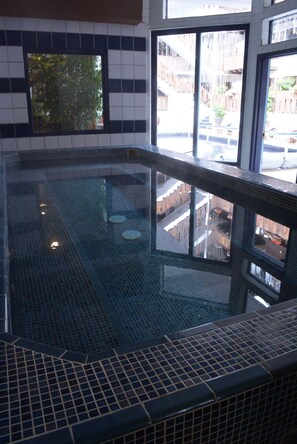 A pool with a tiled floor and a view of the outside through large windows. - Mountain Chalet Aspen (Aspen)