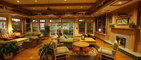 A spacious lobby with wooden flooring, multiple seating areas, and a fireplace.