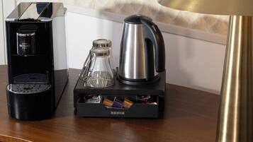 Una cafetera, una jarra de vidrio y un soporte para cápsulas de café sobre una mesa de madera.