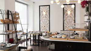 A modern dining area with a buffet setup, including various food items and a decorative light fixture. - Hôtel Elysées Bassano (Paris)