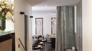 Zona menjador moderna amb un separador de vidre, un ram de flors i taula posta per dinar.