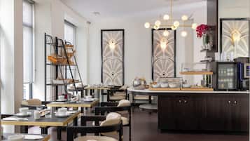 Un comedor moderno con mesas, sillas y una isla central con cafetera y elementos decorativos.