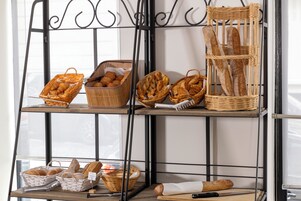 A bakery display with various types of bread and pastries in wicker baskets.