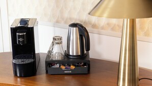 A hotel room with a wooden desk, a coffee maker, a lamp, and a chair. - Hôtel Elysées Bassano (Paris)