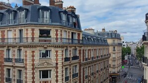 A multi-story building with a classic architectural style, featuring a mix of brick and stone facades, large windows, and balconies. - Hôtel Elysées Bassano (Paris)