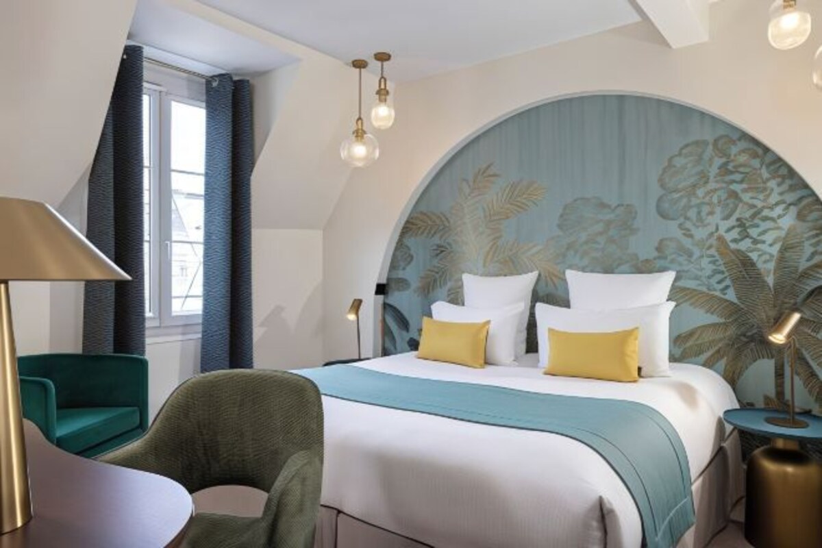 Une chambre d’hôtel avec un lit, une chaise, une lampe et une table de chevet.