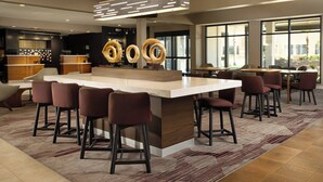 A modern bar area with a central island, bar stools, and a patterned rug. - Courtyard by Marriott Phoenix Mesa (Mesa)